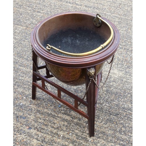 331 - Edwardian copper coal cauldron with a brass swing handle, on a mahogany stand with brass lion mounts... 