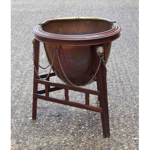 331 - Edwardian copper coal cauldron with a brass swing handle, on a mahogany stand with brass lion mounts... 