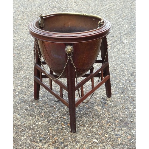 331 - Edwardian copper coal cauldron with a brass swing handle, on a mahogany stand with brass lion mounts... 