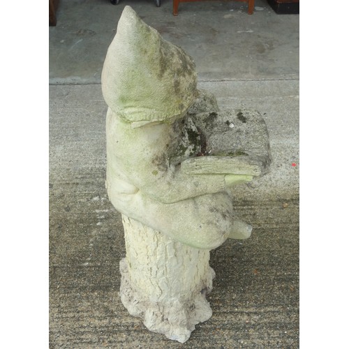 340 - Composition figure of a gnome, sitting crossed legged reading a book, on a composition tree trunk ba... 