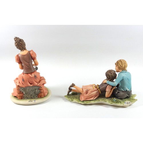 195 - Capodimonte group of a girl and boy about to kiss, W 25.5cm and a group of a woman seated with a pup... 