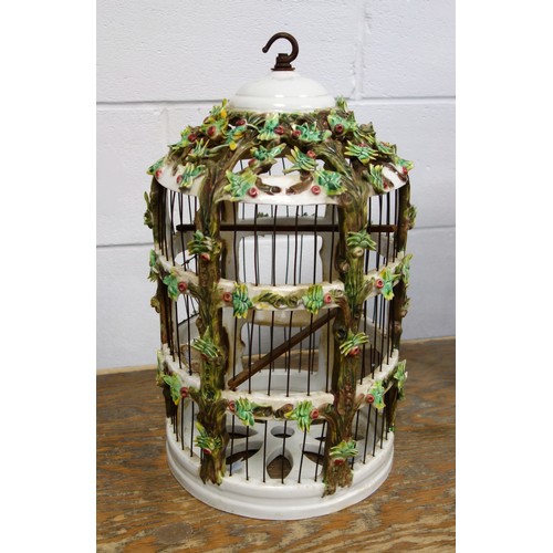 164 - Italian ceramic cylindrical birdcage with all-over encrusted floral decoration, door a/f, with two t... 