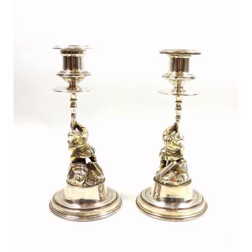20 - Pair of novelty silver candlesticks, each modelled as a gnome or dwarf holding the urn shaped sconce... 
