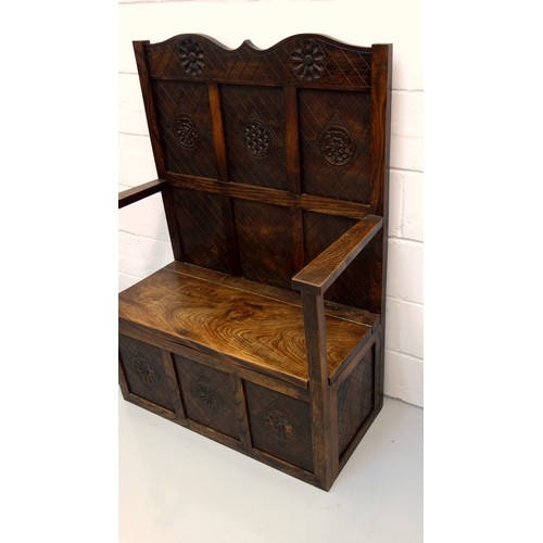 240 - George V elm box seat settle with a panelled back, hinged seat, arms and panelled front, with carved... 