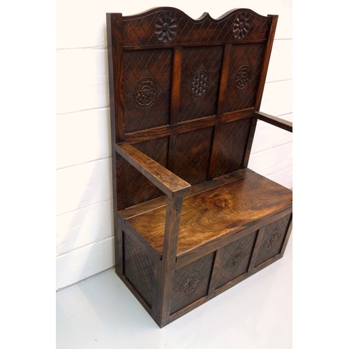 240 - George V elm box seat settle with a panelled back, hinged seat, arms and panelled front, with carved... 