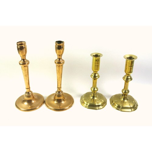 528 - Pair of George II brass candlesticks, each with a tall capital on a knopped baluster column and 