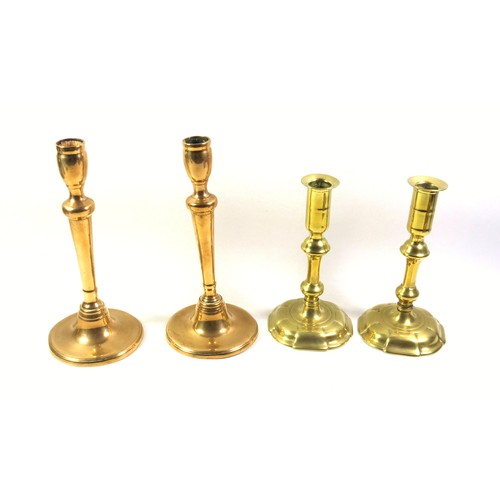 528 - Pair of George II brass candlesticks, each with a tall capital on a knopped baluster column and 