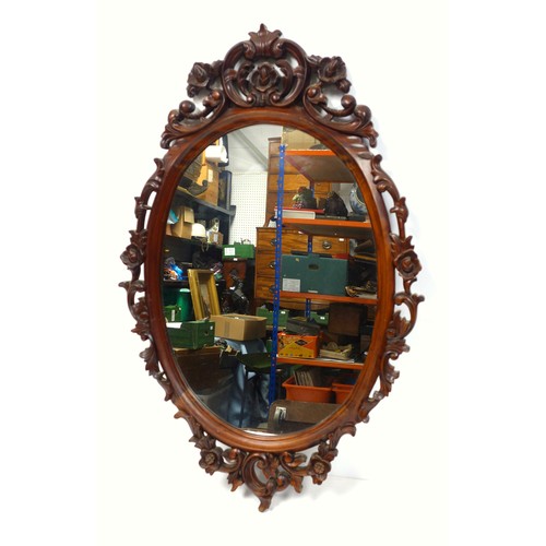 400 - Wall mirror with an upright oval plate, in a mahogany finish moulded scroll and floral frame, 109 x ... 