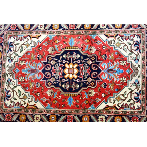 254 - Persian rug, the madder field with an indigo lozenge, ivory spandrels, and all-over floral decoratio... 