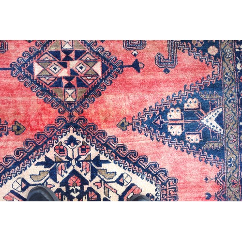 270 - Persian rug, the abrashed coral field with 3 linked latch-hook medallions, and indigo spandrels, wit... 