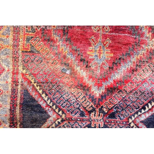 270 - Persian rug, the abrashed coral field with 3 linked latch-hook medallions, and indigo spandrels, wit... 