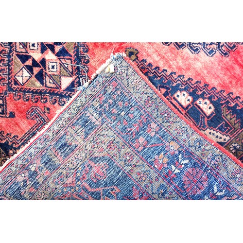 270 - Persian rug, the abrashed coral field with 3 linked latch-hook medallions, and indigo spandrels, wit... 