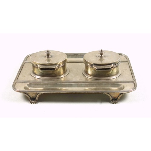 490 - George V silver ink stand of rounded rectangular form with 2 oval inkwells, the hinged covers enclos... 