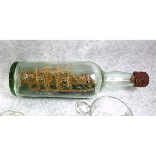 845 - Model ship in a glass bottle with 4 masts, coastline with buildings and a lighthouse behind, W.29.5c... 