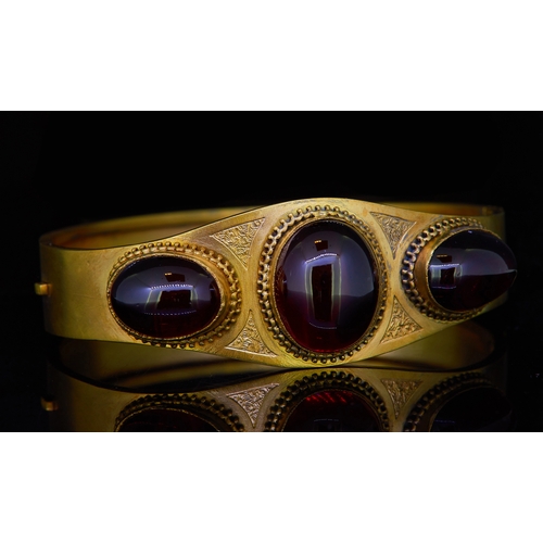 43 - ANTIQUE VICTORIAN GARNET HINGED BANGLE, set to the top with 3 cabochon cut oval garnets, accentuated... 