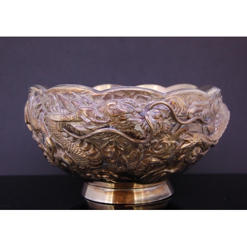 247 - SILVER DRAGON BOWL, decorated all around with a dragon in relief through the waves. With scallobed r... 