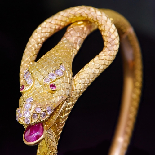 11 - A 19th CENTURY CHINEASE DRAGON BANGLE, in yellow precious metal. The tongue set with a ruby of 1.29 ... 