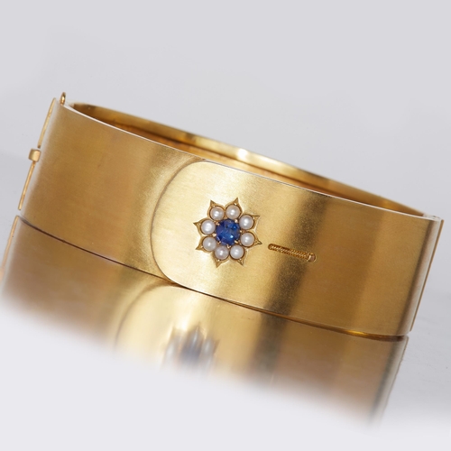 323 - VICTORIAN SAPPHIRE AND PEARL HINGED BANGLE, in 15 ct. gold. Set to the top with a blue sapphire and ... 