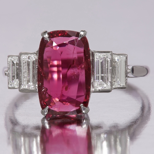 29 - RUBY AND DIAMOND RING, Set to the center with a large ruby of approx. 11.2 x 7.14 mm. Flanked with 2... 