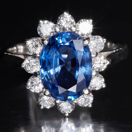 6 - SAPPHIRE AND DIAMOND CLUSTER RING, Set with a central oval blue sapphire of approx. 3.31 ct. Surroun... 