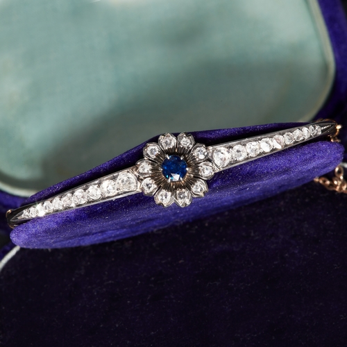 9 - VICTORIAN SAPPHIRE AND DIAMOND CLUSTER HINGED BANGLE, the center of floral design, set with a blue s... 