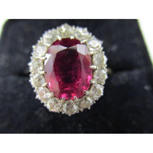 58 - An 18ct gold ring set with fourteen diamonds around a ruby which is approximately 9mm x 7mm