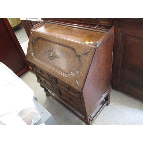 429 - An early 20th century oak bureau with carved decoration, standing on carved legs with stretchers