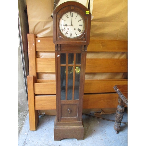 427 - An early 20th century oak arched top grandmother clock with visible pendulum door