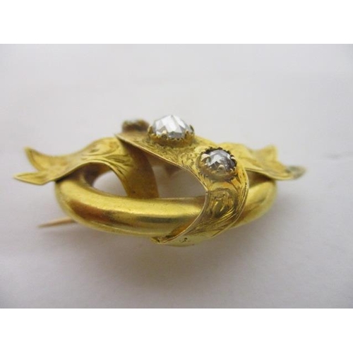 115 - A Victorian gold coloured metal and three stone diamond brooch, fashioned as ribbons on an oval back... 