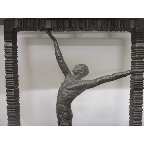 125 - A contemporary cast bronze hall table having a black marble top, over a man with outstretched arms, ... 