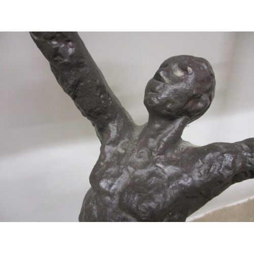 125 - A contemporary cast bronze hall table having a black marble top, over a man with outstretched arms, ... 