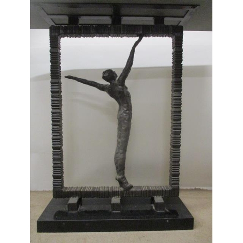 125 - A contemporary cast bronze hall table having a black marble top, over a man with outstretched arms, ... 