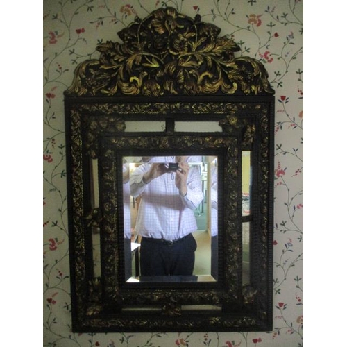 192 - WITHDRAWN  A late 19th century continental black painted and gilt pressed metal mirror, decorated wi... 