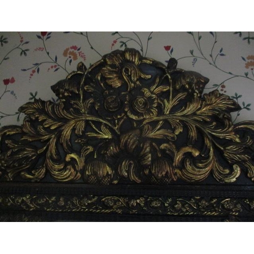 192 - WITHDRAWN  A late 19th century continental black painted and gilt pressed metal mirror, decorated wi... 