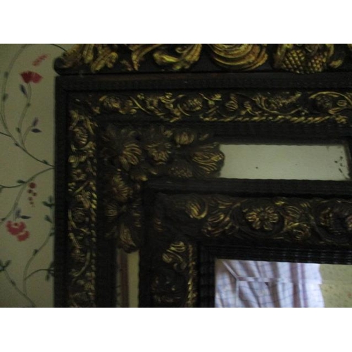 192 - WITHDRAWN  A late 19th century continental black painted and gilt pressed metal mirror, decorated wi... 