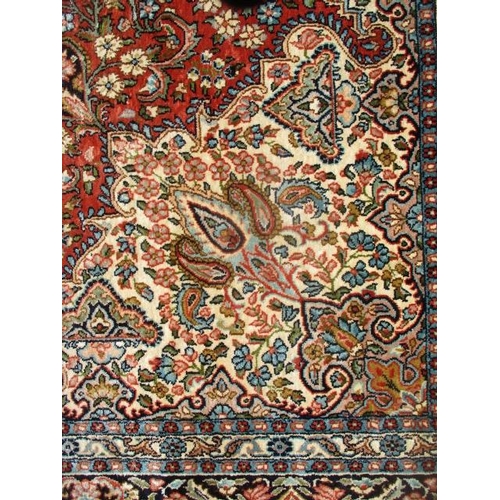 212 - An Indian cotton carpet with a central medallion, palmets, flowing branches and flowers on a red gro... 