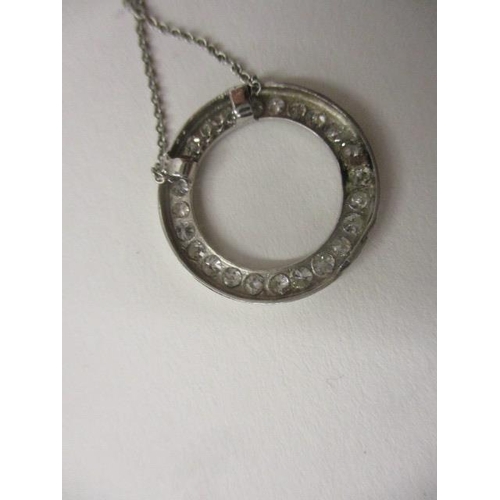 241 - A platinum circular pendant set with a band of diamonds, on a fine platinum chain