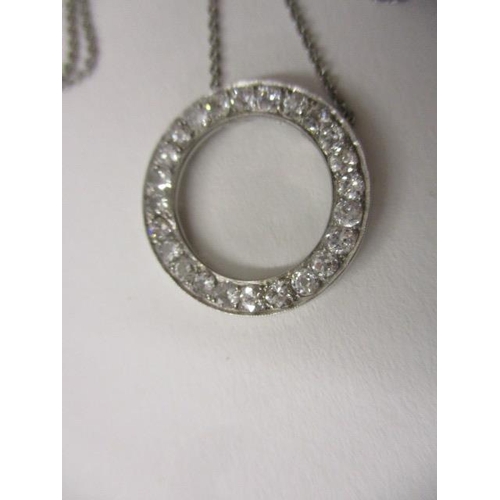 241 - A platinum circular pendant set with a band of diamonds, on a fine platinum chain