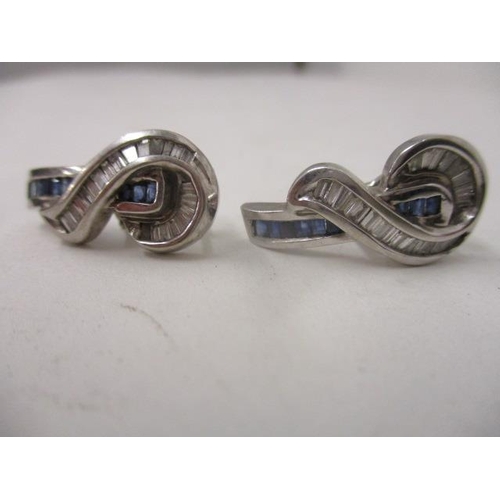 283 - A pair of white gold coloured metal earrings, each set with a line of princess cut sapphires and dia... 