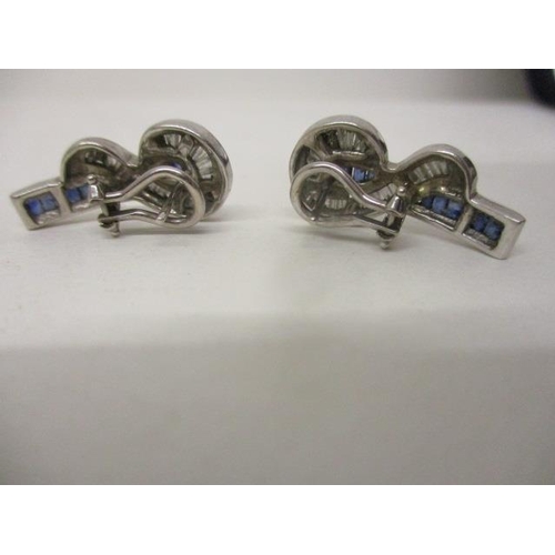 283 - A pair of white gold coloured metal earrings, each set with a line of princess cut sapphires and dia... 