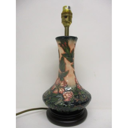 293 - A Moorcroft pottery vase design table lamp with a tall, narrow neck decorated with leaves and flower... 