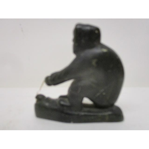 298 - A Canadian carved, green soapstone figure of an Inuit catching a fish through a hole in the ice, 3 1... 