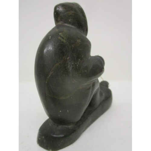 298 - A Canadian carved, green soapstone figure of an Inuit catching a fish through a hole in the ice, 3 1... 