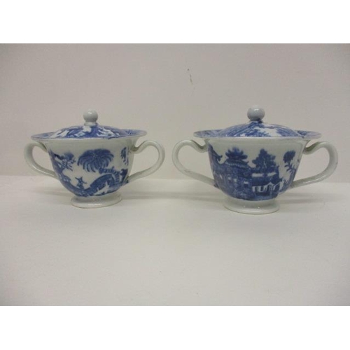 74 - A pair of Pearlware blue and white custard cups, with domed covers and twin handles, decorated with ... 