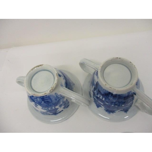 74 - A pair of Pearlware blue and white custard cups, with domed covers and twin handles, decorated with ... 