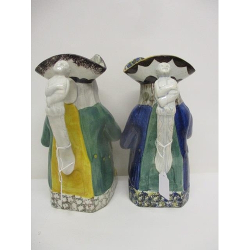 76 - An early 18th century and a 19th century Toby jug, each holding a jug and a glass on a plinth, 10