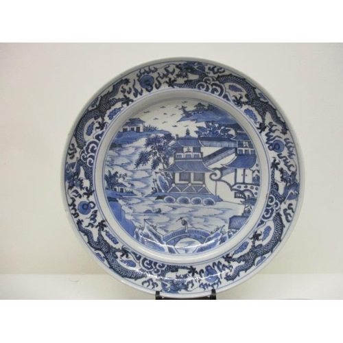 82 - Three late 18th century Chinese plates, one decorated with a band of dragons, a river, a bridge, a f... 