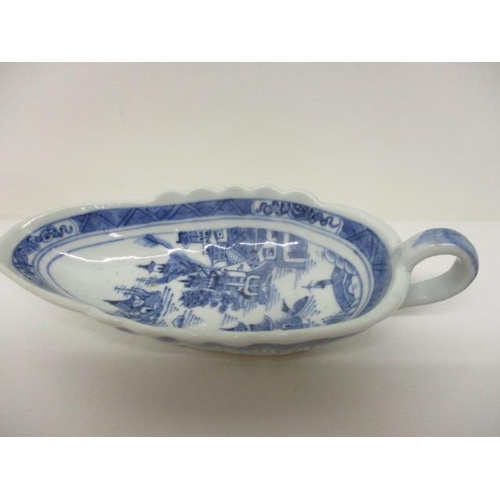 83 - An early 19th century Chinese Canton blue and white sauce boat decorated with a river scene and buil... 