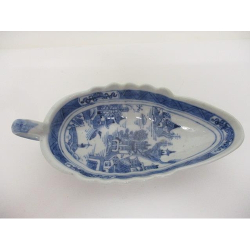 83 - An early 19th century Chinese Canton blue and white sauce boat decorated with a river scene and buil... 