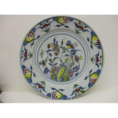 90 - An 18th century polychrome Delft dish decorated with flowers and fruit, 13 1/4